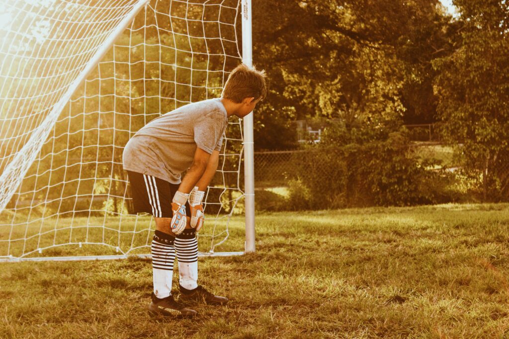 youth soccer goal keeper standing inside of soccer net