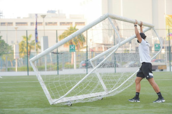 coach setting up goals on field
