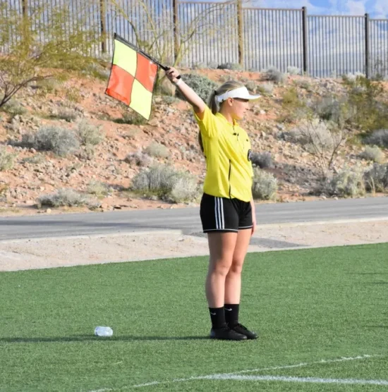 girl standing on sideline holding a flag to show direction