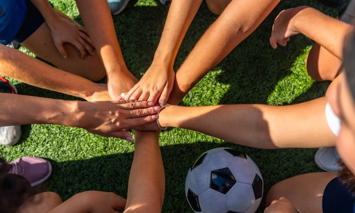 Photo of soccer players in a huddle and piling their hands together